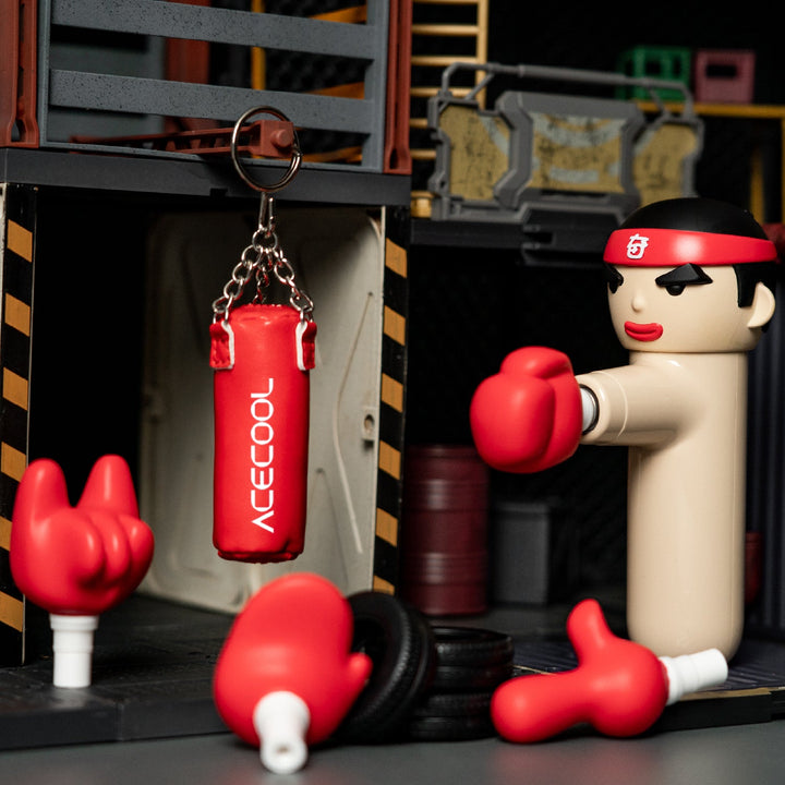ACECOOL KungFu Boxer Massagegerät mit Zubehör, roter Mini-Boxsack mit Logo und austauschbare Massageaufsätze, inszeniert in Trainingsumgebung.