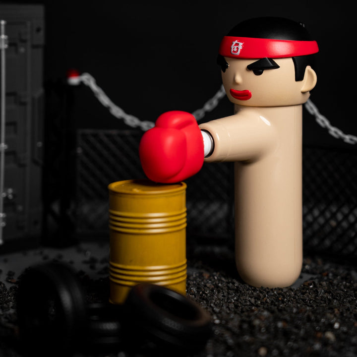 ACECOOL KungFu Boxer Massagegerät in beige, dargestellt beim Training mit einem gelben Metallfass, roter Boxhandschuh nach vorne ausgestreckt.
