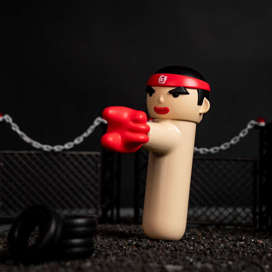 ACECOOL Handmassagegerät KungFu Boxer in beige mit rotem Stirnband und Boxhandschuhen, stehend in einer Trainingsszene mit Reifen und Zaun.