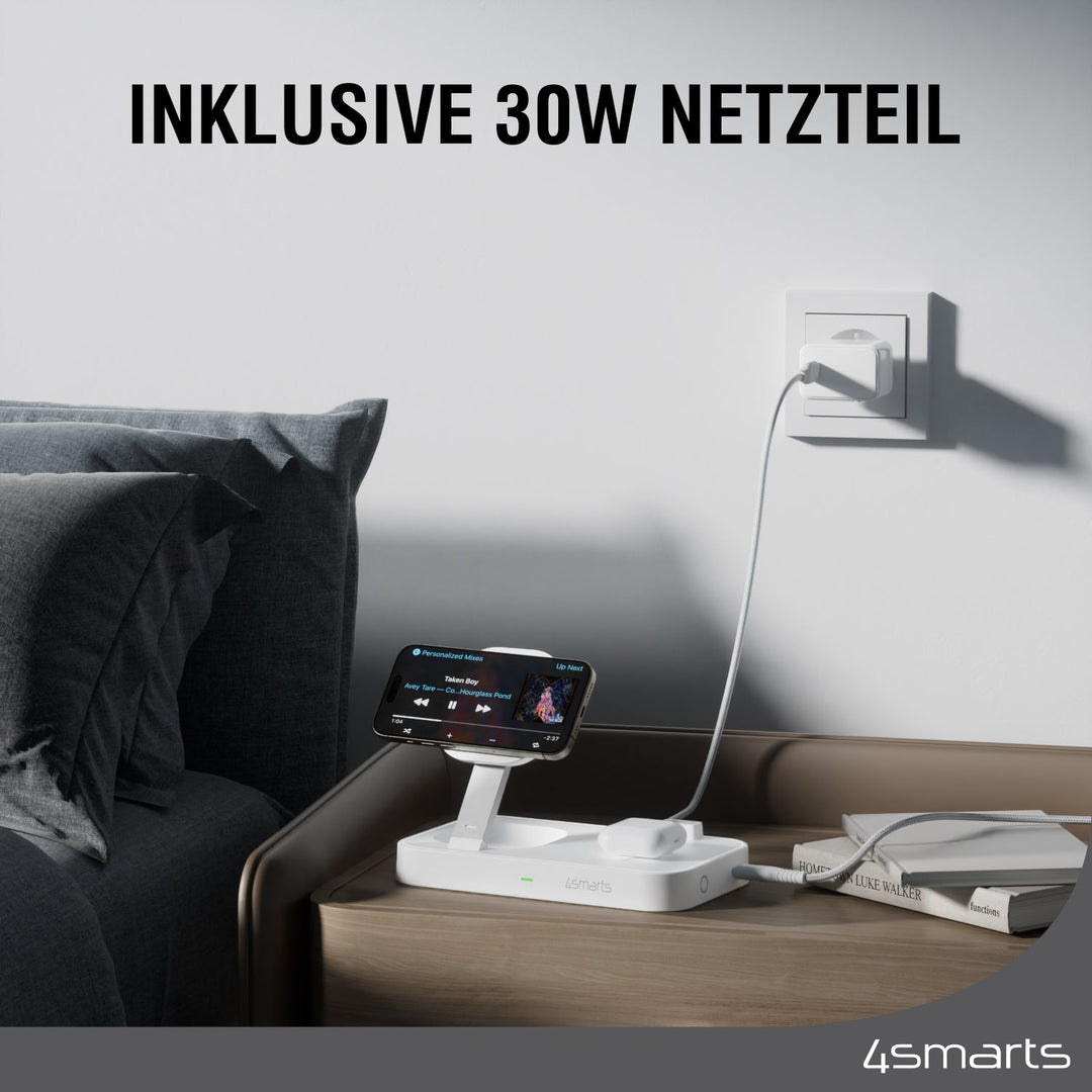 Die Qi2 Ladestation Trident Weiß auf einem Nachttisch neben einem Bett, ein Smartphone wird auf der Ladestation geladen. Der Text darüber lautet "INKLUSIVE 30W NETZTEIL".